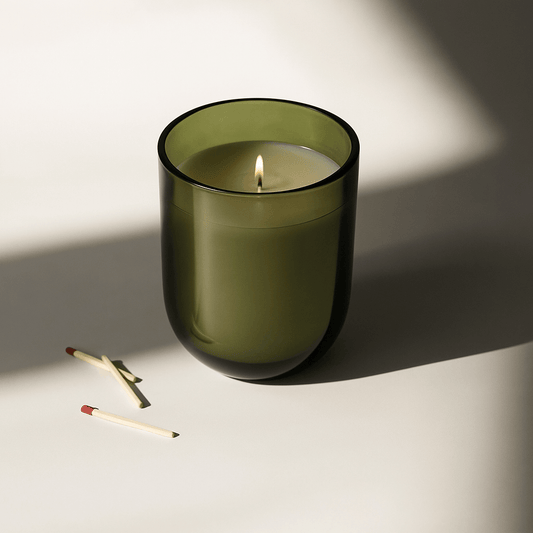 Elegant green candle with a warm flame, surrounded by matches, perfect for monthly self-care rituals.