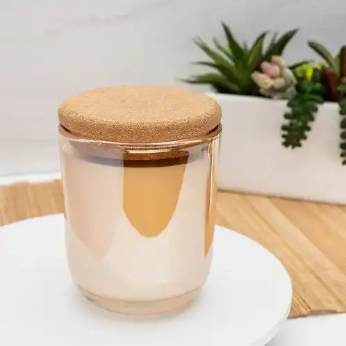 Elegant candle with cork lid on a white plate, surrounded by succulents for a serene self-care ambiance.